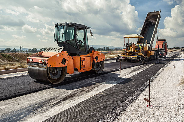 Pavement machine laying fresh asphalt or bitumen on top of the gravel base during highway construction